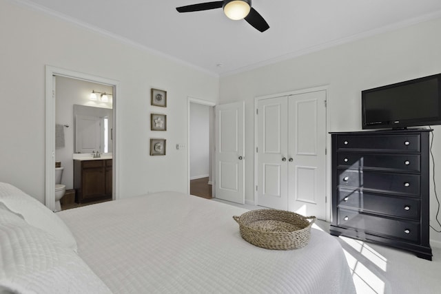 carpeted bedroom featuring ornamental molding, a closet, connected bathroom, and ceiling fan