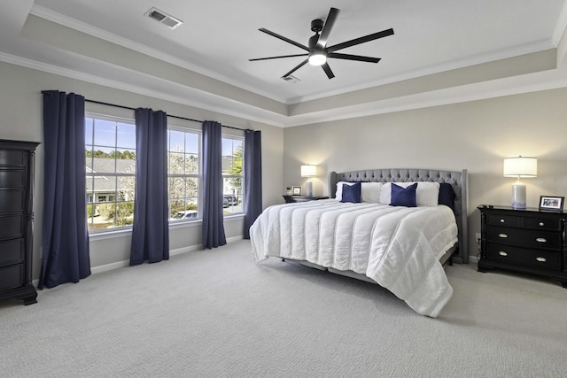 bedroom with visible vents, baseboards, ornamental molding, a tray ceiling, and carpet