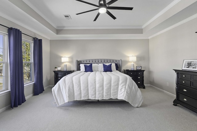 bedroom featuring light carpet, baseboards, a tray ceiling, and crown molding