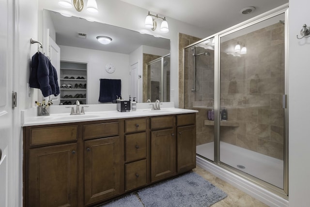 bathroom featuring a stall shower, visible vents, a sink, and double vanity