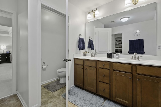 bathroom featuring visible vents, a sink, toilet, and double vanity