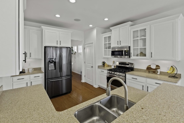 kitchen featuring stainless steel appliances, recessed lighting, glass insert cabinets, white cabinets, and a sink