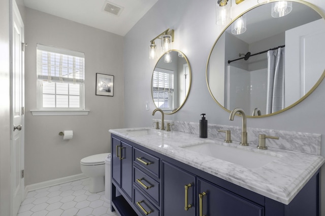 full bath with toilet, double vanity, a sink, and visible vents