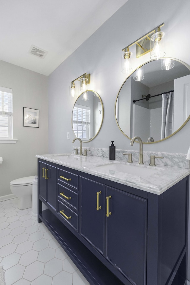 full bath with visible vents, a sink, toilet, and double vanity