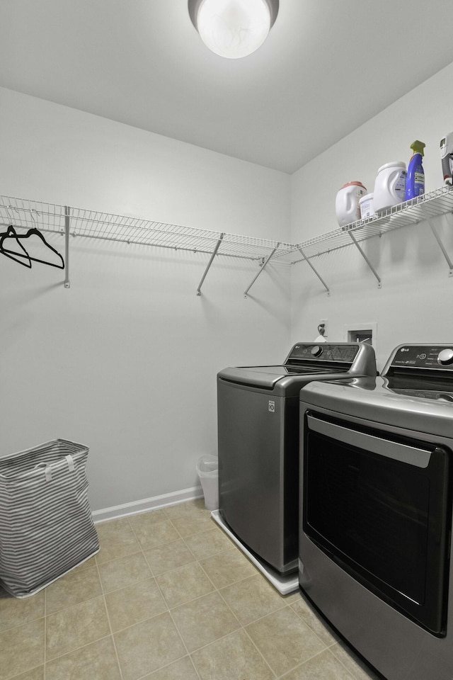 laundry room featuring washing machine and dryer, laundry area, light tile patterned flooring, and baseboards