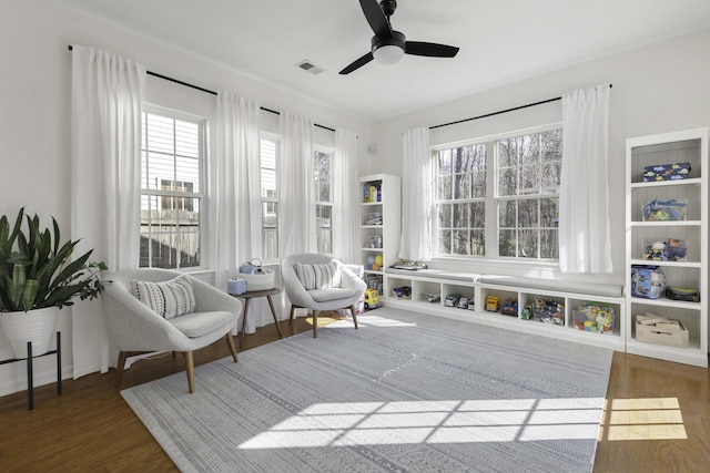 sitting room with wood finished floors, visible vents, and a ceiling fan