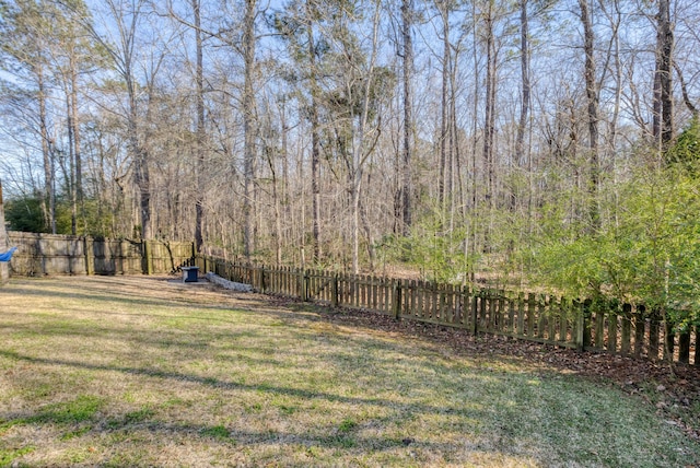 view of yard featuring a wooded view and a fenced backyard