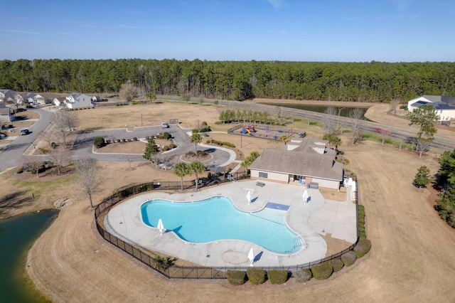 view of swimming pool featuring fence and a wooded view