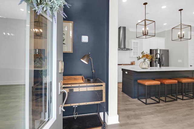 779 Forrest Dr, Charleston, SC 29492 - bar area with wall chimney exhaust hood, stainless steel fridge with ice dispenser, a chandelier, light wood-style flooring, and baseboards