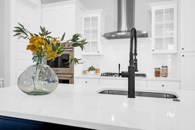 779 Forrest Dr, Charleston, SC 29492 - kitchen with wall chimney range hood, tasteful backsplash, white cabinets, glass insert cabinets, and double wall oven