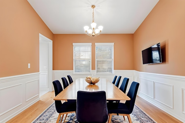 dining space featuring wainscoting, light wood finished floors, and an inviting chandelier