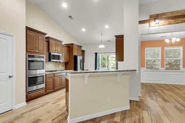 kitchen with appliances with stainless steel finishes, light wood-type flooring, visible vents, and a kitchen bar