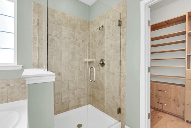 bathroom with a stall shower, wood finished floors, and a bath