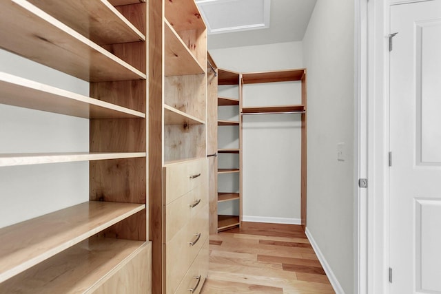 spacious closet with light wood-type flooring and attic access