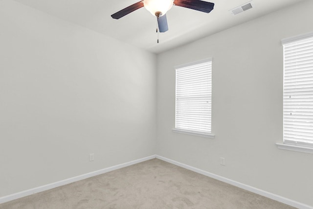 spare room featuring a ceiling fan, light colored carpet, visible vents, and baseboards