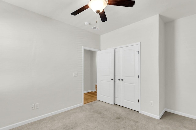 unfurnished bedroom with a closet, light colored carpet, visible vents, a ceiling fan, and baseboards