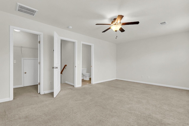 unfurnished bedroom with baseboards, visible vents, a walk in closet, and light colored carpet