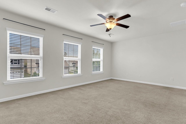 carpeted spare room featuring ceiling fan, visible vents, and baseboards