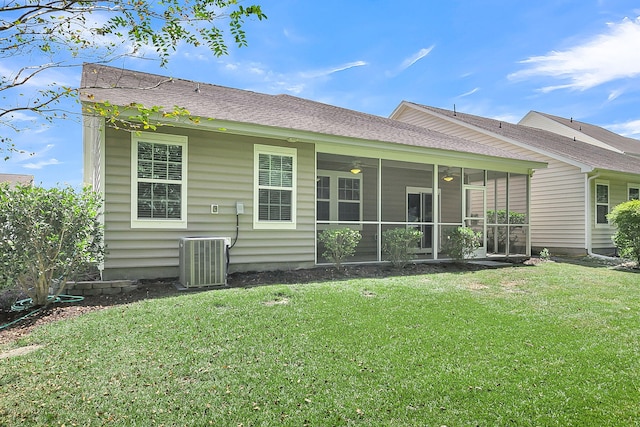 back of property with central AC unit, a shingled roof, a sunroom, a ceiling fan, and a yard