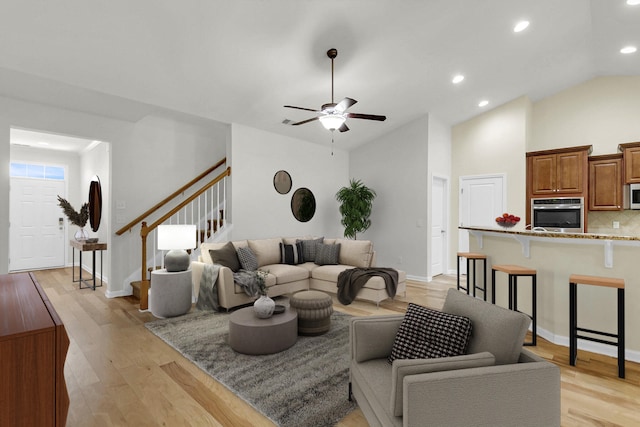 living area with baseboards, ceiling fan, stairway, light wood-type flooring, and recessed lighting