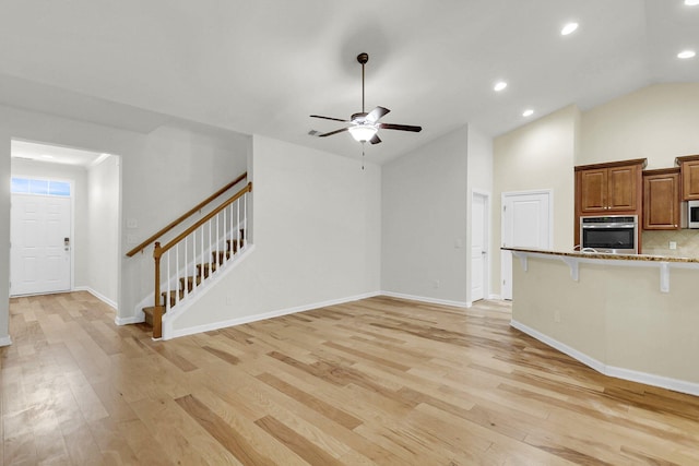 unfurnished living room with recessed lighting, a ceiling fan, light wood-type flooring, baseboards, and stairs