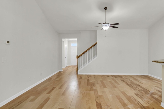 spare room with light wood-style floors, stairs, baseboards, and a ceiling fan