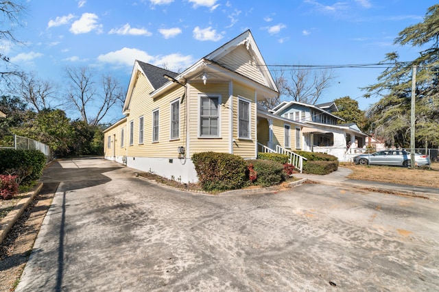 view of property exterior with concrete driveway and fence