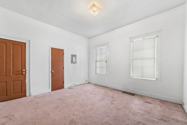 empty room featuring visible vents, carpet floors, a textured ceiling, and baseboards