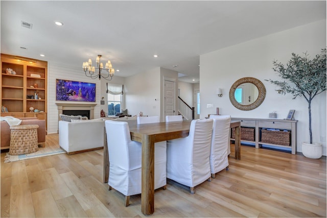 dining area featuring visible vents, light wood-style flooring, recessed lighting, an inviting chandelier, and a fireplace