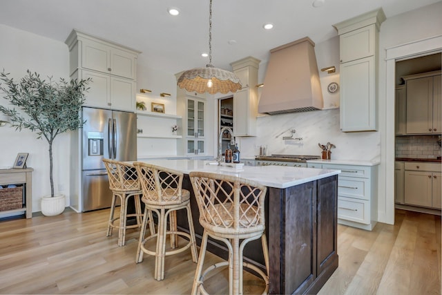 kitchen with premium range hood, a breakfast bar, decorative backsplash, stainless steel fridge, and open shelves