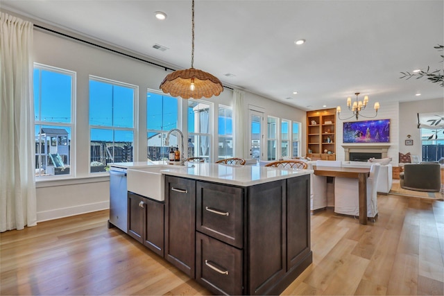 kitchen with a wealth of natural light, open floor plan, dark brown cabinets, and a sink