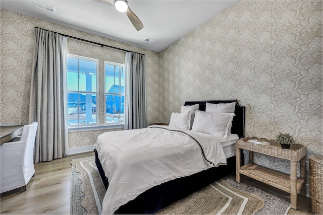 bedroom featuring visible vents, ceiling fan, wallpapered walls, and light wood-style floors