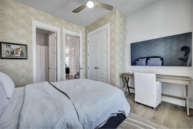 bedroom with visible vents, wood finished floors, wallpapered walls, baseboards, and ceiling fan