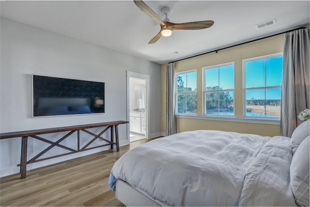 bedroom featuring visible vents, ensuite bathroom, baseboards, and wood finished floors