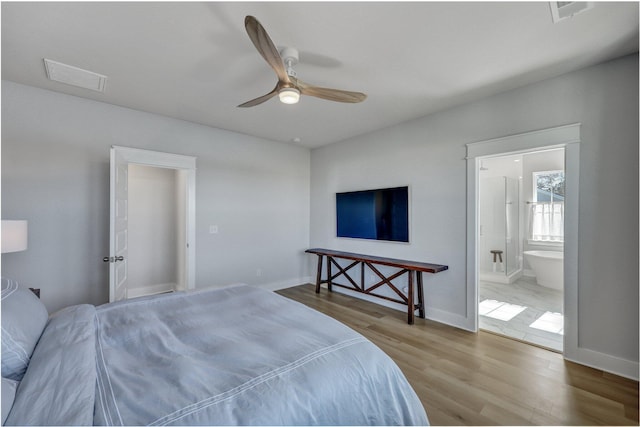 bedroom with visible vents, connected bathroom, baseboards, and wood finished floors