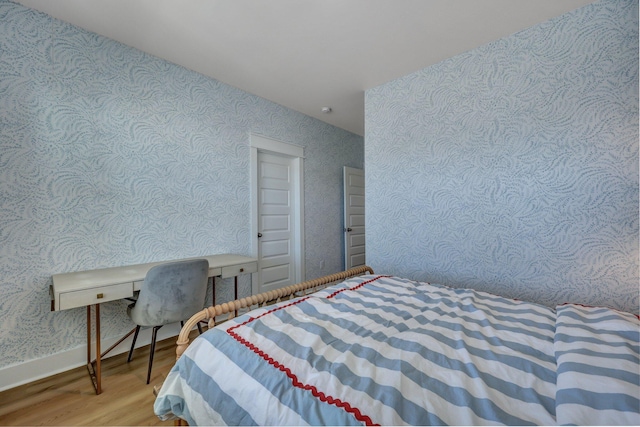 bedroom with wallpapered walls, wood finished floors, and baseboards