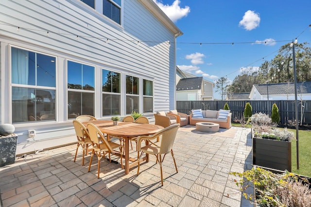 view of patio with outdoor dining space, an outdoor living space with a fire pit, and fence