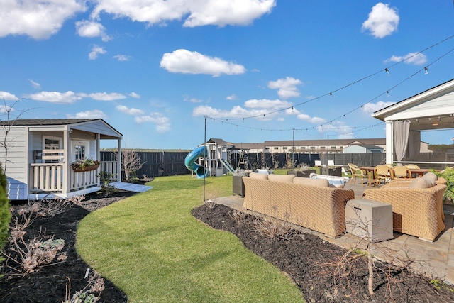 view of yard featuring an outbuilding, an outdoor living space, a fenced backyard, a playground, and a patio area