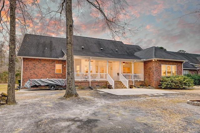 back of property with a ceiling fan, roof with shingles, crawl space, a porch, and brick siding