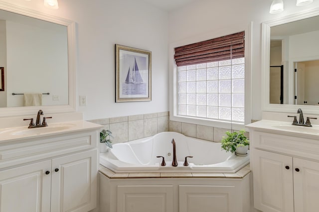 full bath with two vanities, a sink, and a jetted tub