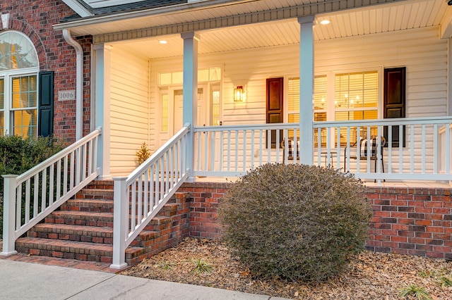 entrance to property with brick siding, roof with shingles, and a porch