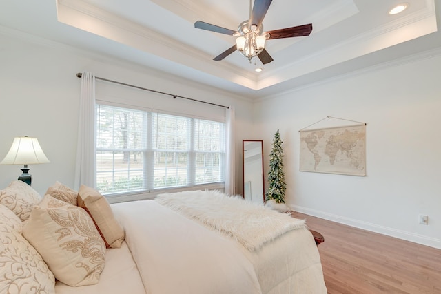 bedroom featuring recessed lighting, wood finished floors, baseboards, ornamental molding, and a tray ceiling