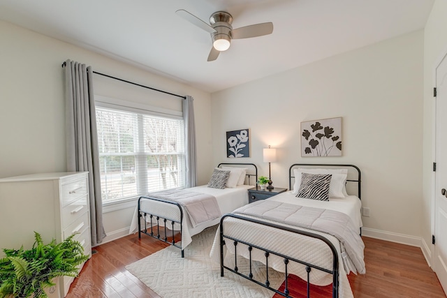 bedroom with a ceiling fan, baseboards, and wood finished floors