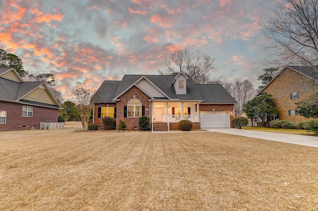 view of front of home with brick siding, a yard, covered porch, concrete driveway, and crawl space