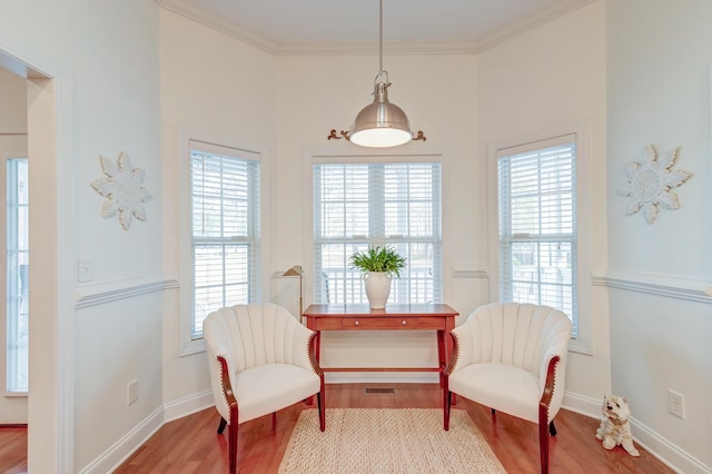 sitting room with ornamental molding, plenty of natural light, wood finished floors, and baseboards