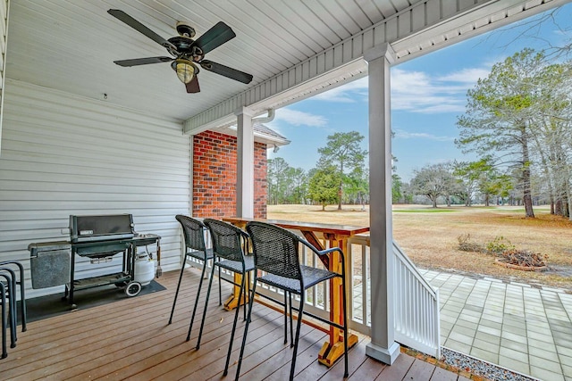 deck with outdoor dry bar, ceiling fan, and grilling area