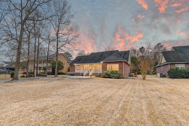 view of front of home featuring a front lawn, cooling unit, and brick siding