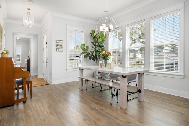 dining space with hardwood / wood-style floors, baseboards, a chandelier, and ornamental molding