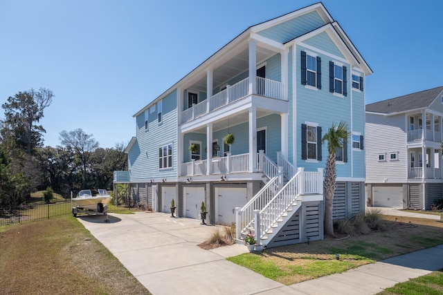 coastal home featuring covered porch, stairs, concrete driveway, a garage, and central air condition unit