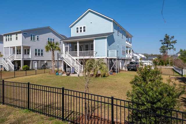 rear view of house with stairs, a lawn, a residential view, and a fenced backyard